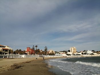 Beach by buildings against sky in city