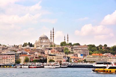 Boats on river by buildings and hagia sophia against sky