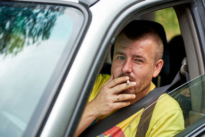 Portrait of man smoking cigarette while sitting in car