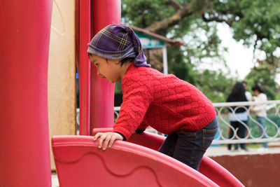Side view of girl climbing on outdoor play equipment at playground