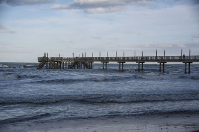 Wooden posts on pier over sea against sky