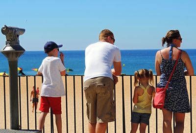 Rear view of people standing against sea