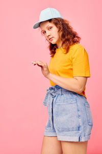 Young woman standing against yellow background