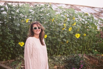 Happy woman in sunglasses standing at sunflower field