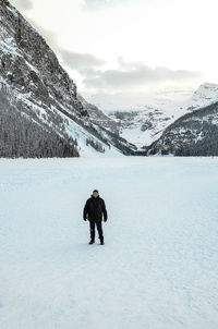 Full length of man standing on snow covered landscape against sky