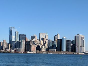 City at waterfront against blue sky