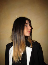 Portrait of beautiful young woman standing against wall