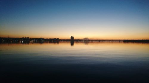 Scenic view of silhouette city against clear sky during sunset