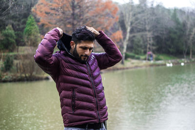 Young man wearing purple jacket against lake