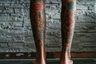 Low section of man with tattoo against brick wall