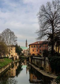 Canal in city against sky