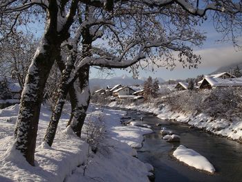 Scenic view of river flowing in village against cloudy sky