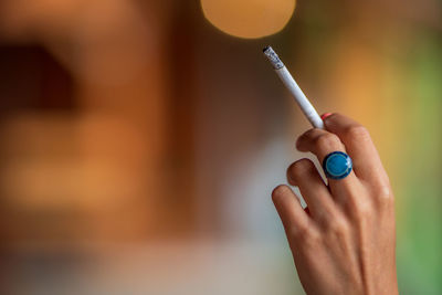 Close-up of cropped hand holding cigarette