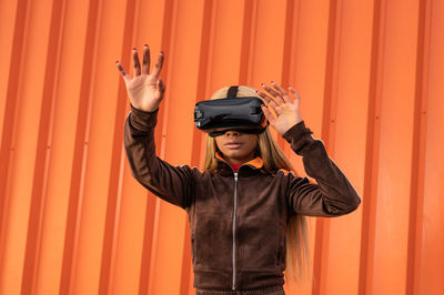 Pretty african american woman using virtual reality glasses on an orange background