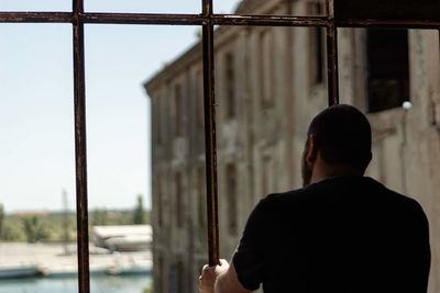 Rear view of man standing against window