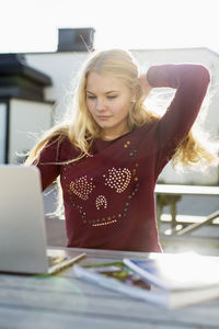 High school girl using laptop on table outdoors