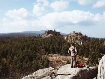 Man standing on mountain against cloudy sky