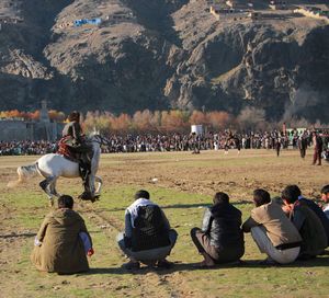 People enjoying horse race against mountain