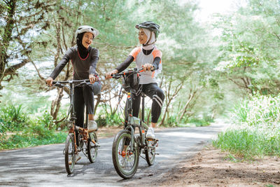 Female friends riding bicycle on road