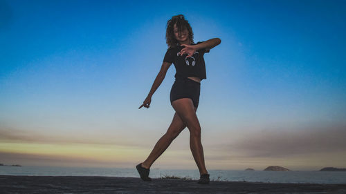 Full length of woman at beach against sky during sunset