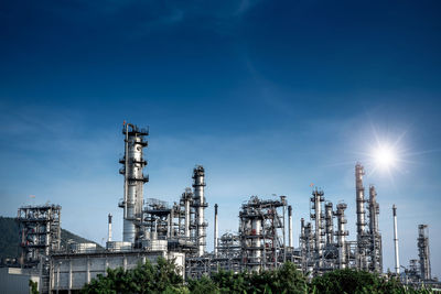 Low angle view of illuminated factory against blue sky