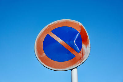 Low angle view of road sign against clear blue sky