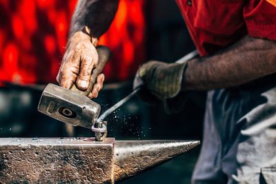 Midsection of blacksmith working on metal