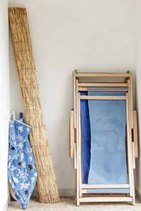 Rolled beach mat and umbrella with folded deck chair leaning on wall