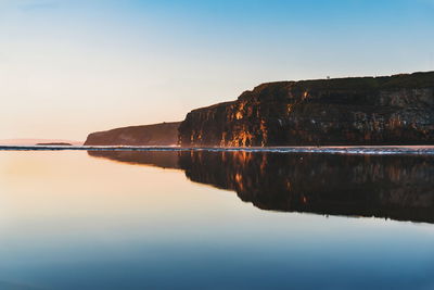 Scenic view of lake against clear sky at sunset