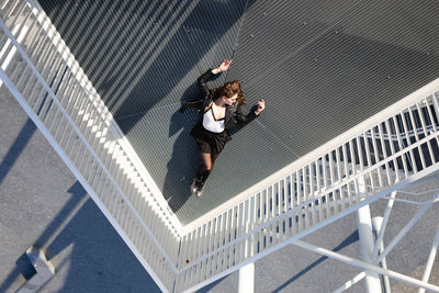 High angle view of young woman lying down on elevated walkway