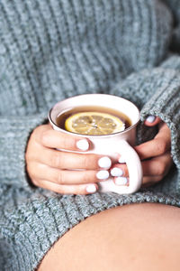 Midsection of woman holding coffee at home