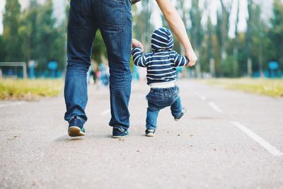 Low section of father with son walking at park