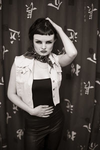 Portrait of young woman standing against wall