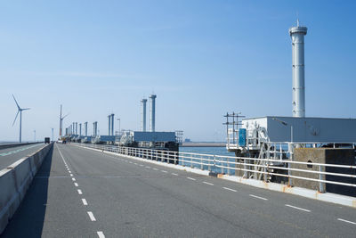 Road by railing against blue sky