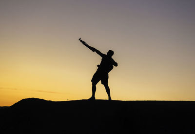 Silhouette man standing on field against clear sky during sunset