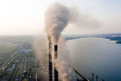 Smoke emitting from factory against sky