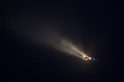 Low angle view of illuminated airplane against sky at night