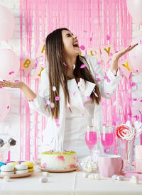 Brunette woman in white party clothes preparing birthday  throwing pink confetti