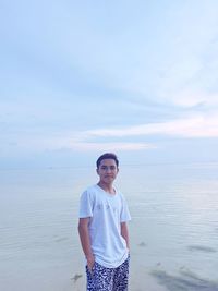 Portrait of smiling man standing on sea shore against sky