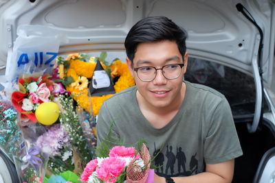 Close-up of smiling young man selling bouquets in car trunk