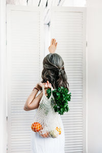 Portrait of woman standing against white wall