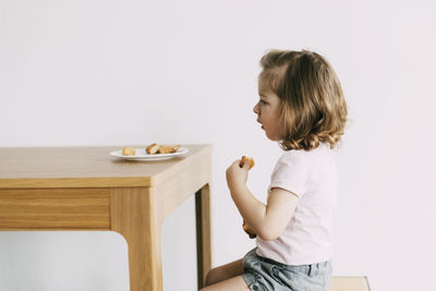 Side view of a girl sitting on table