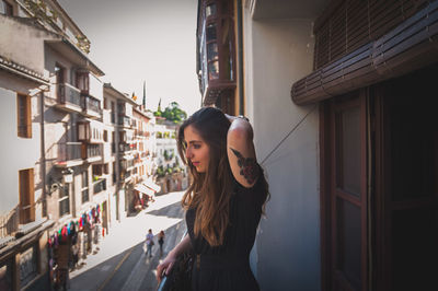 Beautiful woman with hand in hair standing in balcony