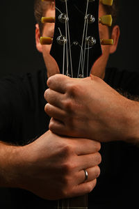 Man holding guitar against black background