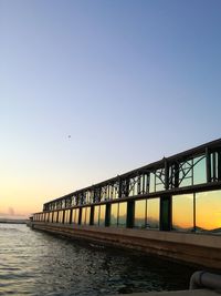 Bridge over sea against clear sky during sunset