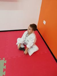 Full length of woman sitting on red wall