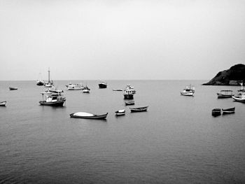 Boats moored in sea against clear sky