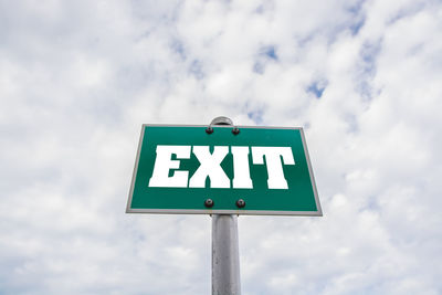 Low angle view of exit sign against cloudy sky