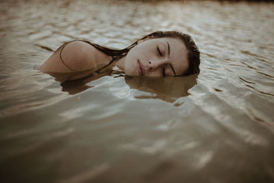 Portrait of young woman lying on swimming pool