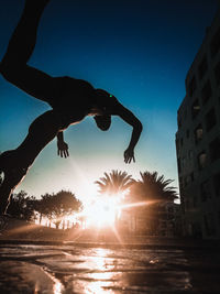 Silhouette man jumping in water against sky